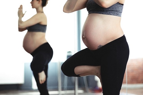 an image of a lady who is heavily pregnant stnading on one leg doing a yoga pose
